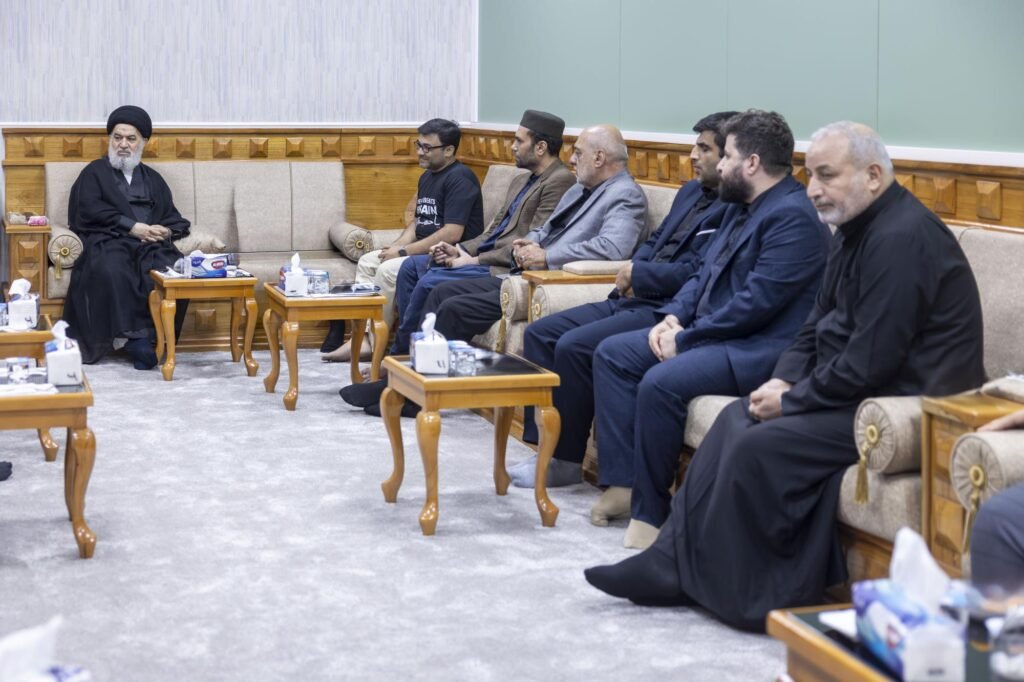 رجل دين معمم يستمع لوفد من الرجال الجالسين على أريكة في قاعة استقبال رسمية.