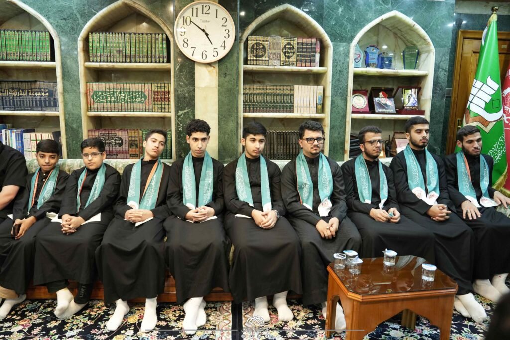 صف من الشباب يرتدون أوشحة خضراء أمام رفوف مكتبة.