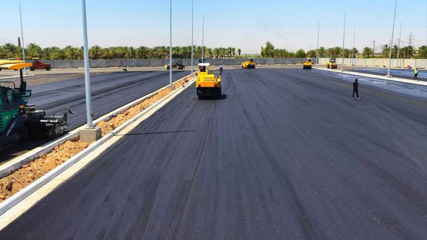 آليات حدل وتبليط تعمل على فرش وتسوية الإسفلت في طريق واسع حديث الإنشاء