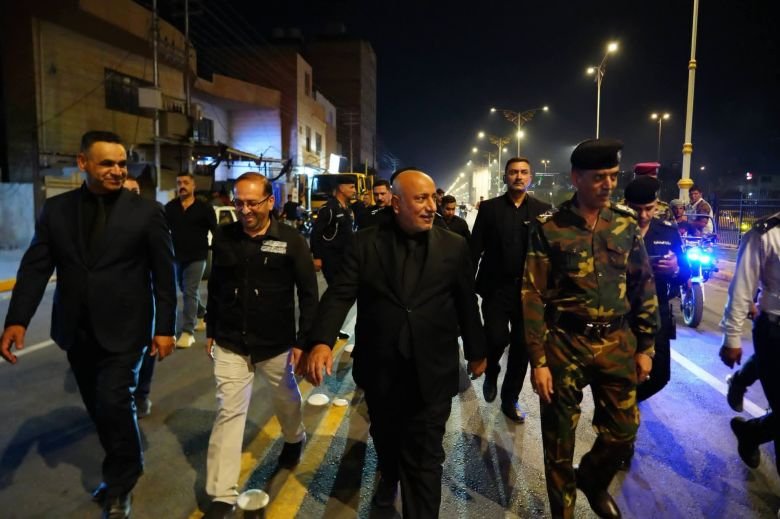 مسؤول وحراسه وضباط يسيرون ليلاً في شارع عراقي.