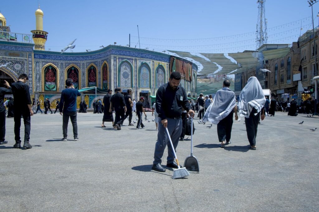 خادم ينظف ساحة العتبة العباسية وسط الزائرين.
