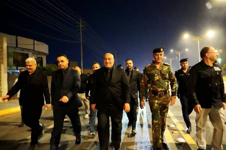 مسؤول مبتسم يتجول ليلاً مع مرافقين وضباط أمن.