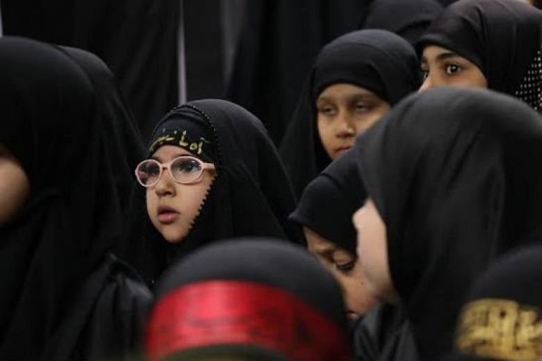فتيات وصغار يرتدون الملابس والحجابات السوداء في تجمع حسيني.