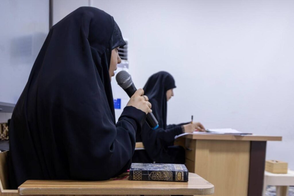إحدى المشاركات تتلو القرآن عبر الميكروفون أثناء الاختبار.