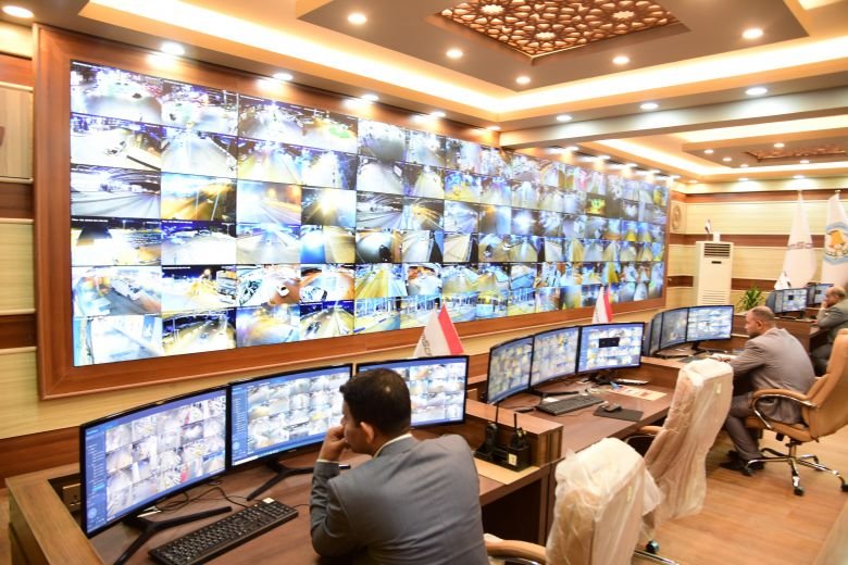 موظفون يراقبون شاشات كاميرات المراقبة في غرفة تحكم.