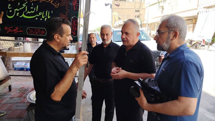 مجموعة من الرجال تتحدث مع أحد القائمين على موكب خدمي في أحد شوارع المدينة