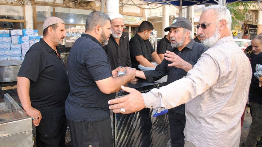 رجال يتبادلون الحديث والتحية أمام موكب يقدم الطعام والمياه