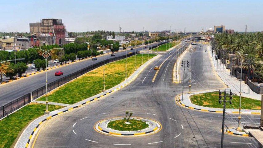 منظر علوي لشارع حديث متعدد المسارات يضم دوّاراً ومساحات خضراء ومواقف جانبية وأعمدة إنارة زخرفية.