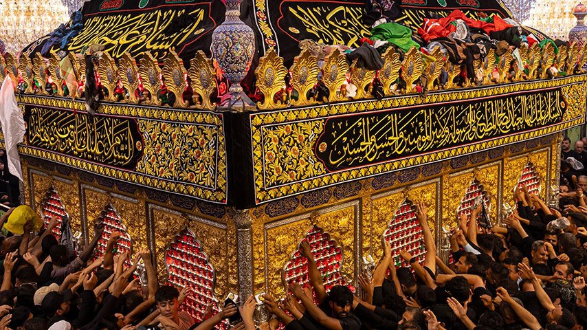 حشود من الزائرين حول شباك ضريح مزخرف في كربلاء.