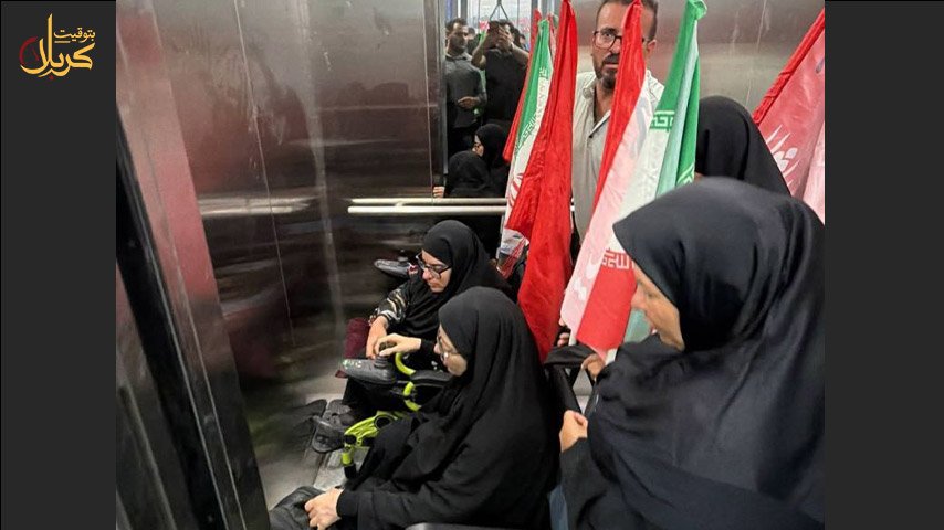 نساء ورجال يرتدون الملابس السوداء ويحملون رايات وأعلاماً داخل مصعد كهربائي، بينهن امرأة تستخدم كرسيًا متحركًا.