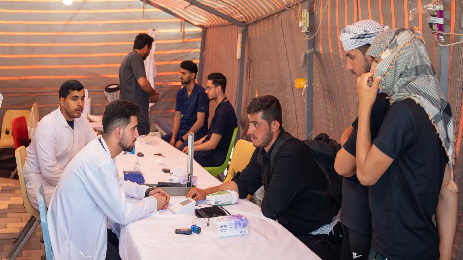 كادر طبي يفحص زائرين داخل خيمة مفرزة طبية ميدانية.