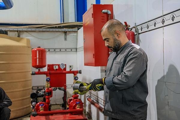 فني صيانة يجري أعمال صيانة لمعدات داخل محطة.