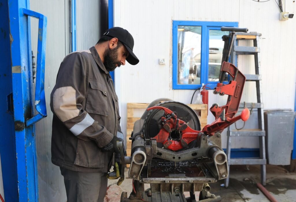 فني يجهز ماكينة تقطيع وتثبيت الأنابيب.