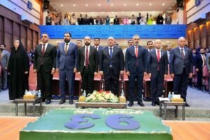 وقوف شخصيات رسمية ومسؤولين في احتفالية أو مؤتمر داخل قاعة احتفالات.