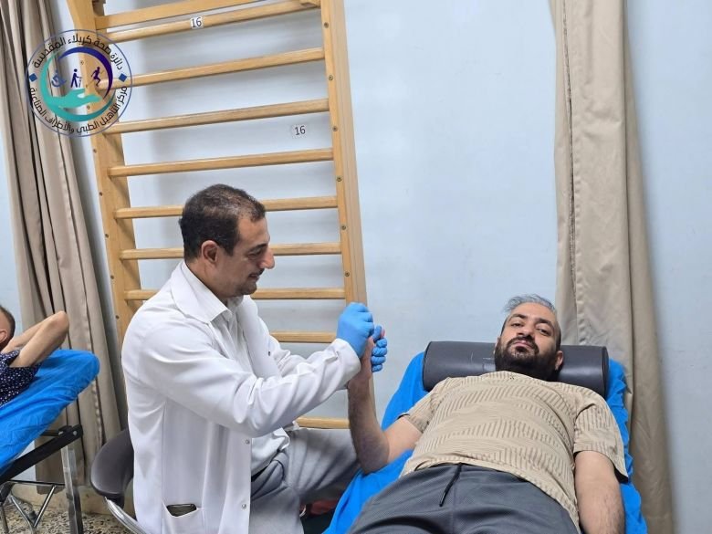 أخصائي علاج طبيعي يقدّم جلسة تأهيل حركي لمريض في مركز التأهيل الطبي والأطراف الصناعية بدائرة صحة كربلاء المقدسة.